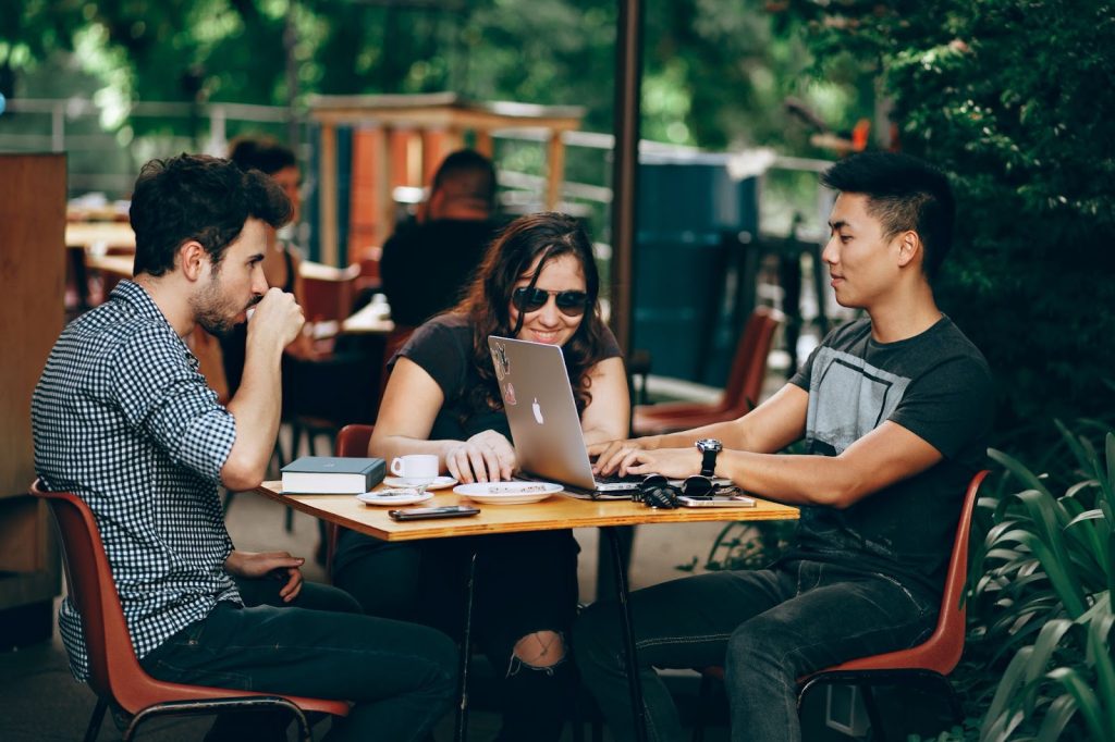 three people on a table with a laptop